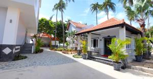 a white house with palm trees in the background at Sand Beach Resort in Mui Ne