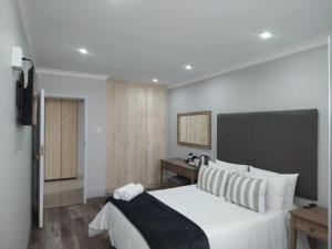 1 dormitorio con 1 cama blanca grande y TV en Blue Owl Guest House, en Mossel Bay