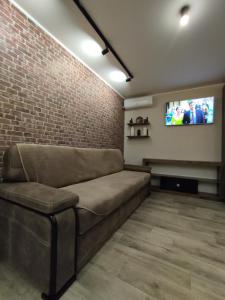 ein Wohnzimmer mit Sofa und Ziegelwand in der Unterkunft Lux apartment in city center in Krementschuk
