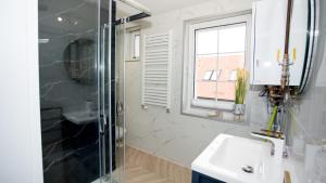 uma casa de banho com um chuveiro e um lavatório. em Apartamenty Sun & Snow Stare Miasto Ustka em Ustka