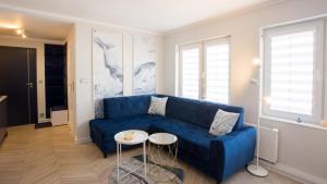 a living room with a blue couch and a table at Apartamenty Sun & Snow Stare Miasto Ustka in Ustka