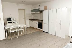 uma cozinha com armários brancos e uma mesa e cadeiras em work & stay apartment em Eitorf
