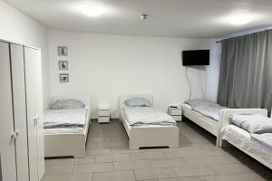 a room with three beds and a flat screen tv at work & stay apartment in Eitorf