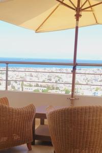 eine Terrasse mit einem Tisch, Stühlen und einem Sonnenschirm in der Unterkunft Appartement à Bizerte in Bizerte