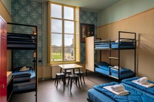 een kamer met een stapelbed, een tafel en een bureau bij Stayokay Hostel Domburg in Oostkapelle