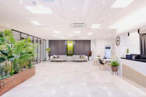 an office lobby with white furniture and potted plants at Hotel Arari in Jeonju