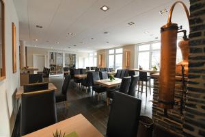 um restaurante com cadeiras pretas, mesas e janelas em Weingut Heinen em Longuich