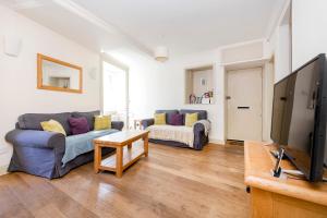 uma sala de estar com um sofá e uma televisão em ALTIDO Charming 2-bed house with Courtyard em Edinburgo