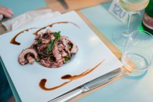 a plate of food on a table with wine glasses at Hotel Le Dune in Sampieri