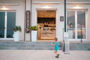 un niño pequeño caminando delante de una tienda en Hotel Le Dune en Sampieri