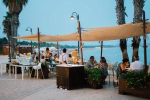 a group of people sitting at tables under an umbrella at Hotel Le Dune in Sampieri