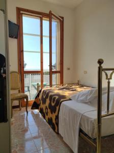 a bedroom with a bed and a large window at Hotel Atlantico in Castiglioncello