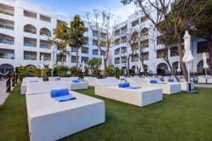 a row of white chairs on the grass in front of a building at Playacartaya in El Portil