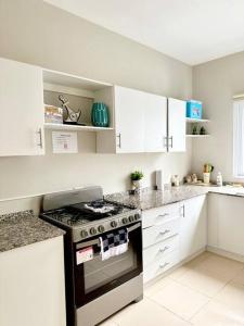 a white kitchen with a stove and white cabinets at Beachfront Flat Brickell@LaCosta in El Zapote