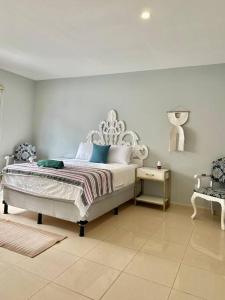 a white bedroom with a bed and a chair at Beachfront Flat Brickell@LaCosta in El Zapote
