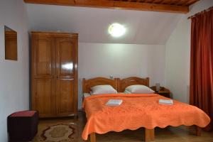 バドゥ・イゼイにあるPensiunea Teodora Telepteanのベッドルーム1室(オレンジ色の毛布付きのベッド1台付)