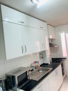 una cocina con armarios blancos y fregadero en Relaxing confortable room, en Valencia