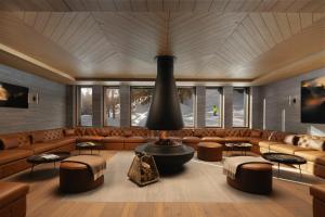 a large room with a couch and tables and windows at Six Senses Crans-Montana in Crans-Montana