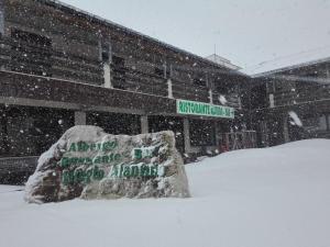 um sinal coberto de neve em frente a um edifício em Hotel Rifugio Alantino em Casamaina