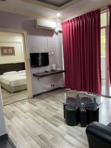 a living room with a glass table and a bed at KUHARA COURT APARTMENT SUITE in Tawau