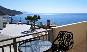 uma varanda com uma mesa e cadeiras e o oceano em Villa Tzortzaki - Dias em Térsa