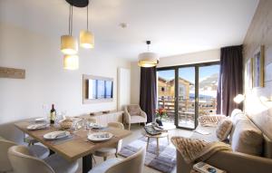 ein Wohnzimmer mit einem Tisch und Stühlen sowie ein Esszimmer in der Unterkunft Résidence Prestige Odalys l'Éclose in L'Alpe-d'Huez