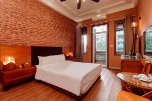 a bedroom with a white bed and a brick wall at Super OYO Capital O 1173 Le Grand Hanoi Hotel - The Ruby in Hanoi