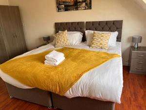a bedroom with a large bed with a yellow blanket on it at Saviour Manor in Kettering