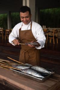 Un homme prépare des poissons sur un grill dans l'établissement Innit Lombok, à Ekas