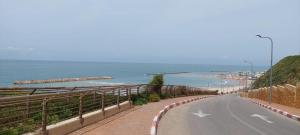 an empty road next to a beach with the ocean at הנביאים 1 נתניה Naveim apartment in Netanya