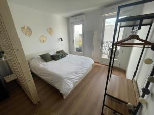 Un pequeño dormitorio con una cama blanca y una ventana en ALP Chartres - Grand studio avec terrasse et parking, en Chartres