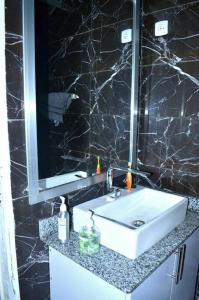 a bathroom with a white sink and a mirror at Bujumbura Sweet Home - Maison bien équipée avec voiture gratuite in Bujumbura
