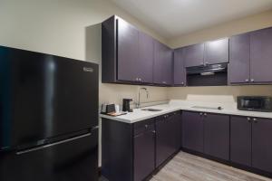 a kitchen with purple cabinets and a black refrigerator at Scottish Inns & Suites Hitchcock-Santa Fe in Hitchcock
