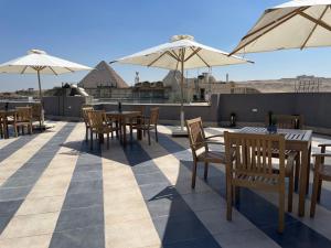 a patio with tables and chairs and umbrellas on a roof at Locanda Museum Hotel in Giza