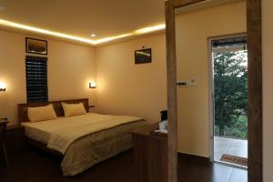 1 dormitorio con 1 cama y puerta corredera de cristal en Agronest Farm & Resort By Teal Luxury Stay, en Wayanad