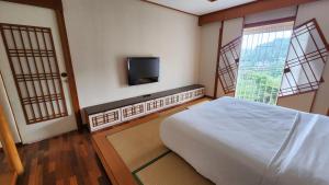 1 dormitorio con 1 cama y TV de pantalla plana en Japanese Style Villa at Dago Bandung 4BR Soo Maison, en Bandung