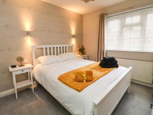 a bedroom with a white bed with a yellow blanket at The Beach Huts in Hornsea