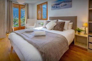 a bedroom with a large bed and a chair at Chalet Aravista - OVO Network in Le Grand-Bornand