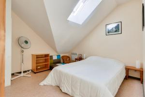 a bedroom with a white bed in a attic at À deux pas de la plage, jolie maison pour 4 in Notre-Dame-de-Monts