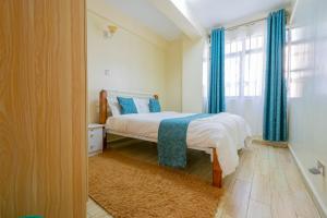 1 dormitorio con 1 cama con cortinas azules y ventana en Art-inspired 3BR Apartment en Nairobi