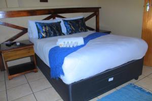 a bedroom with a large bed and a night stand at Butterflytree Guest House in Phalaborwa