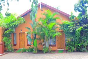 une maison orange avec des palmiers devant elle dans l'établissement Butterflytree Guest House, à Phalaborwa