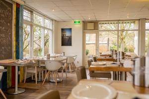 - une salle à manger avec des tables, des chaises et des fenêtres dans l'établissement Hotel Kijkduin, à Domburg