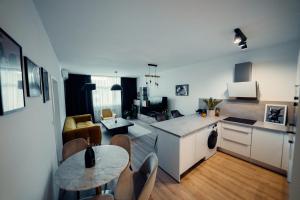 TIFFANY Apartment Hotel في براتيسلافا: مطبخ وغرفة معيشة مع طاولة وكراسي