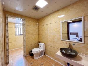 a bathroom with a toilet and a sink and a mirror at Yijingju Humanistic Inn in Zhangjiajie