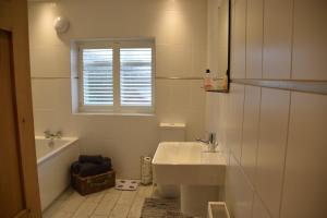 a white bathroom with a sink and a window at Bluebell Cottage , 36 Main Street in Alveston