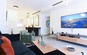 a living room with a couch and a tv on a wall at Kineret sheli- 4Bedrooms luxury apartment with stunning lake view in Tiberias
