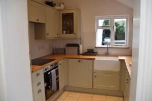 a kitchen with yellow cabinets and a sink and a window at Bluebell Cottage , 36 Main Street in Alveston