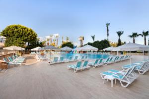 uma piscina com cadeiras e guarda-sóis azuis e brancos em Euphoria Comfort Beach Alanya em Mahmutlar