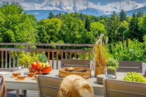 a table with bowls of fruit on a deck with mountains at Chalet Les Vosnes - OVO Network in Domancy